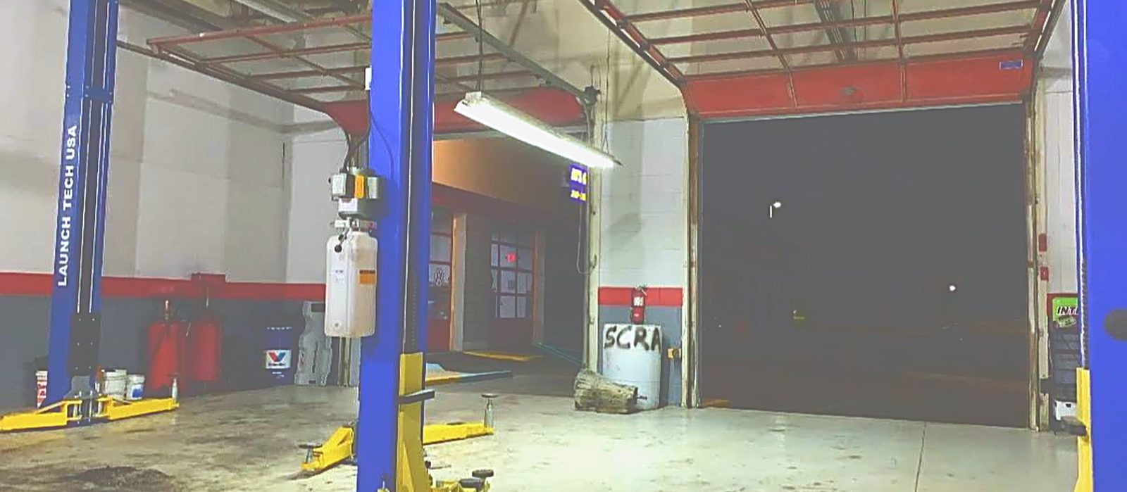 An empty bay with the arms swung clear and the roll-up door open onto the lot.